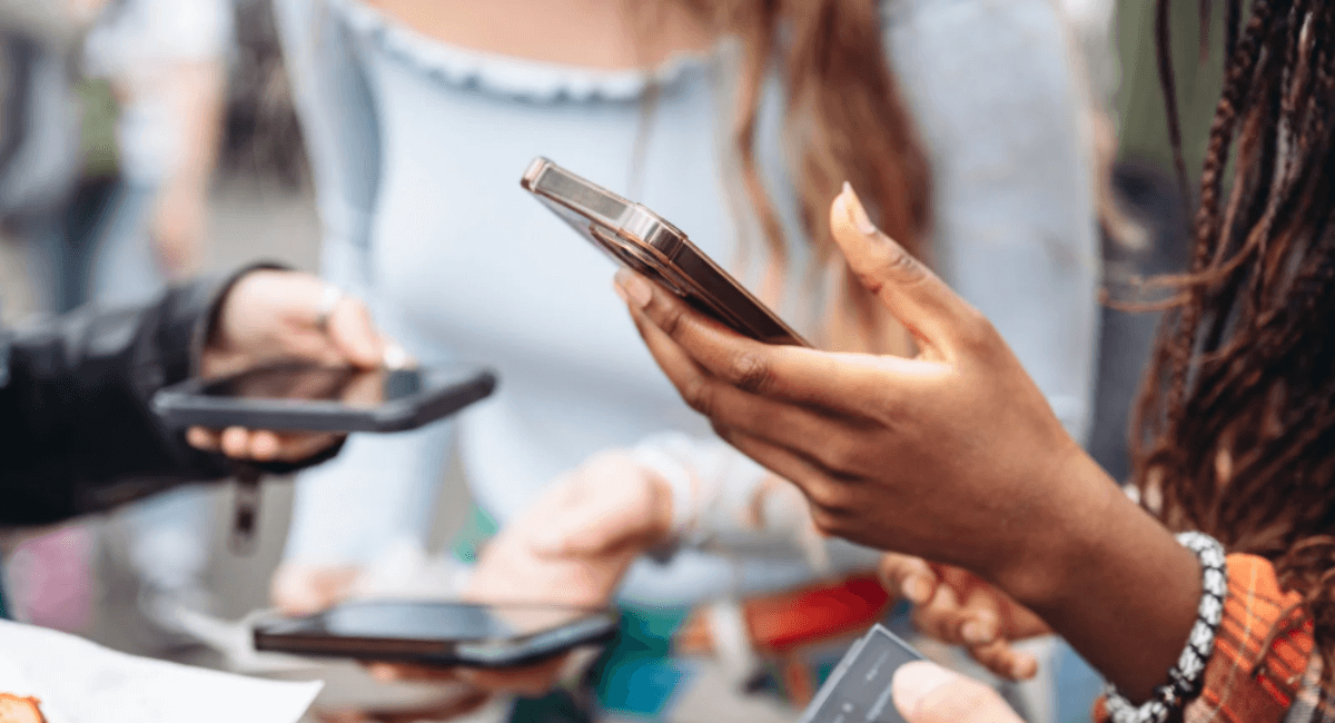 Close-up of several people holding smartphones and browsing, showing social and mobile-first search behavior.