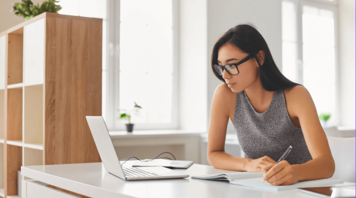 Business professional researching suppliers online and taking notes during the B2B buying process.