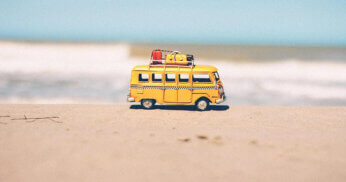 Miniature bus sits on a sunny beach.