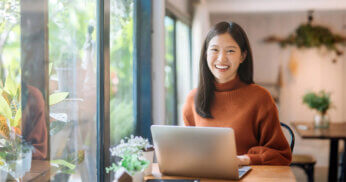 Smiling woman working on laptop.