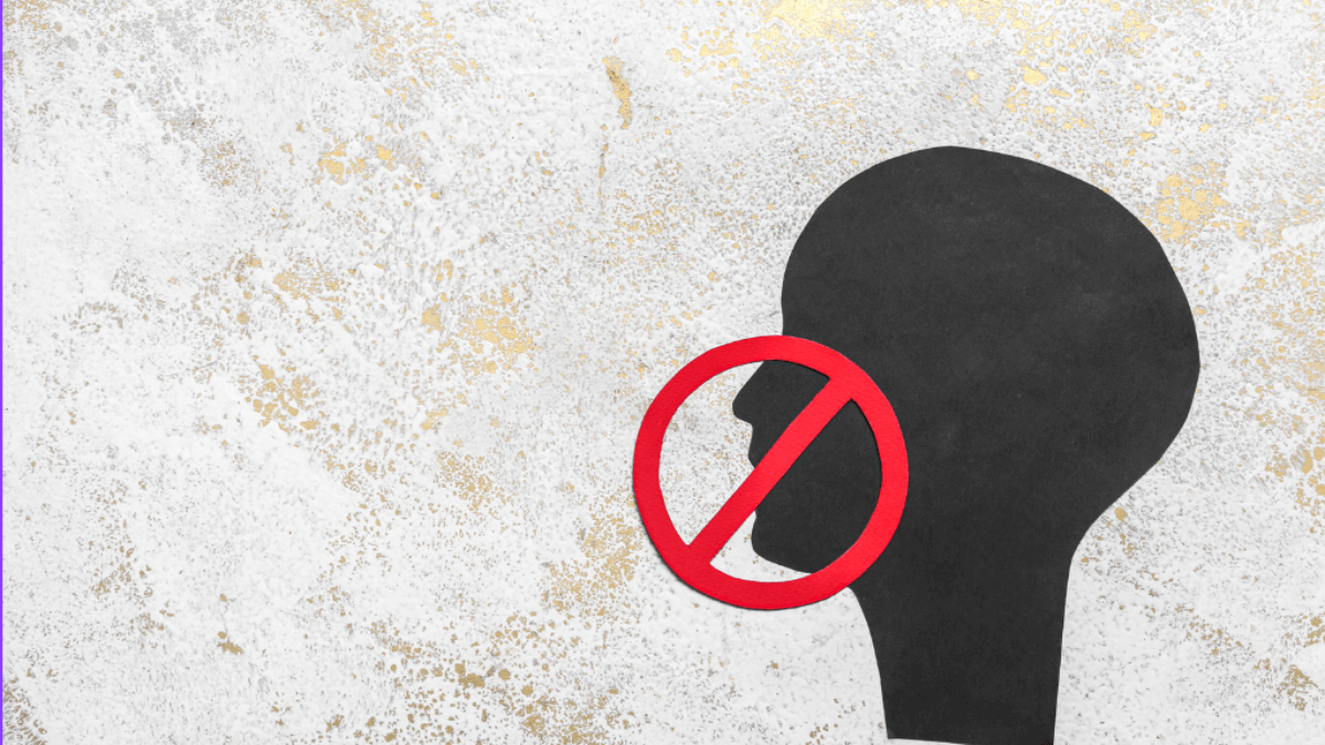 Black human head silhouette overlaid with a red ‘no’ symbol on a textured background, representing censorship or restricted speech.