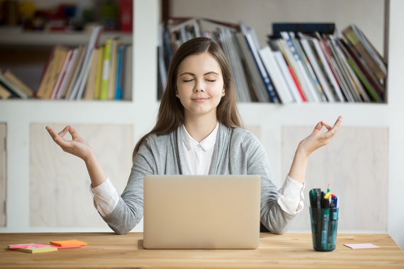 Calm woman meditating with laptop.