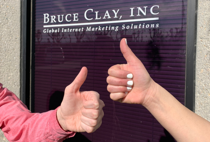 Thumbs up in front of Bruce Clay brand sign.