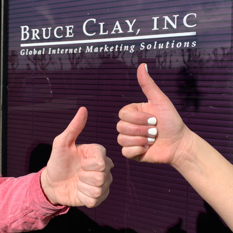 Thumbs up in front of Bruce Clay brand sign.