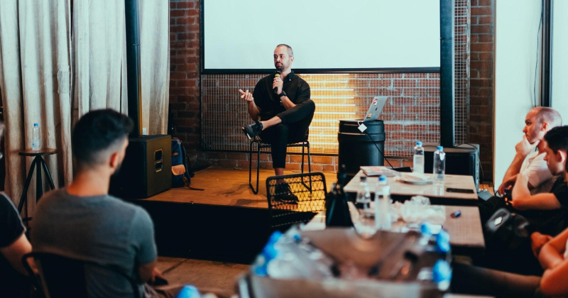 Expert seated, speaking to a group.