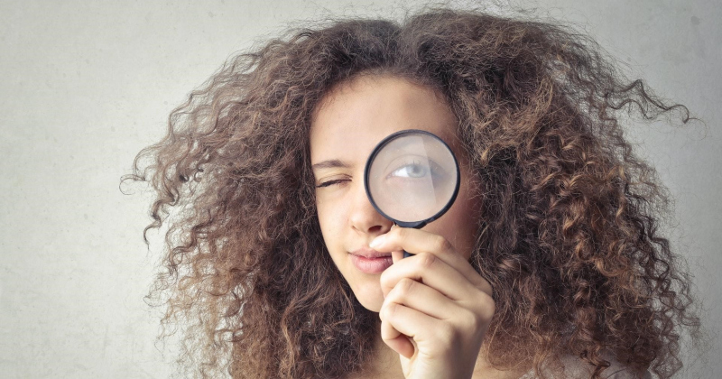 Woman with magnifying glass examining keywords.