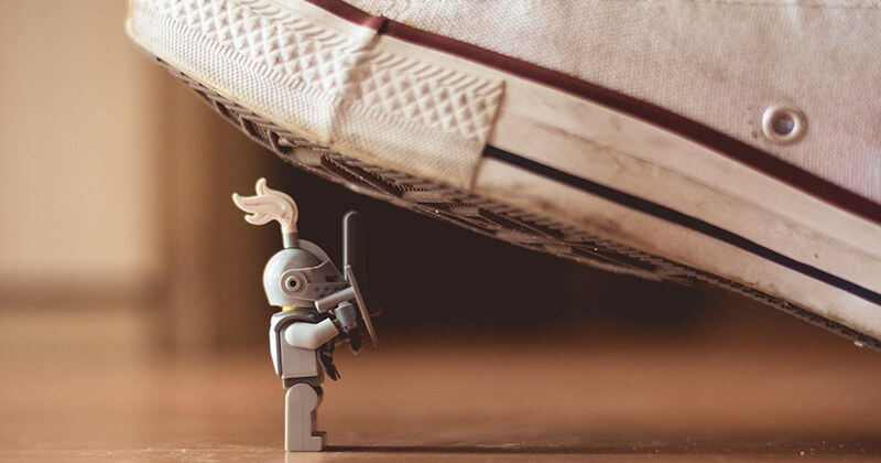 A small toy knight battles a giant shoe in a David versus Goliath scenario.