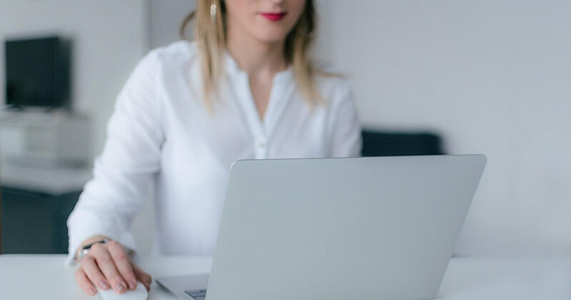 Marketing professional writes a catchy headline on a laptop.