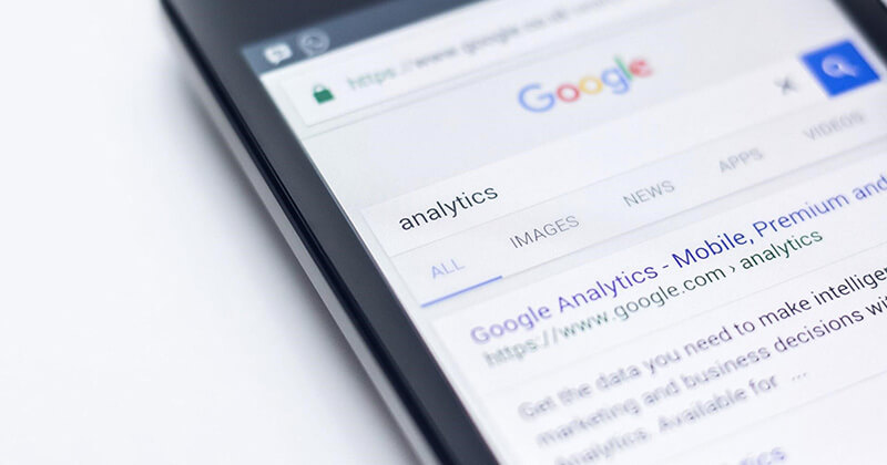 Mobile device displays Google search engine results page for the query 'analytics.'