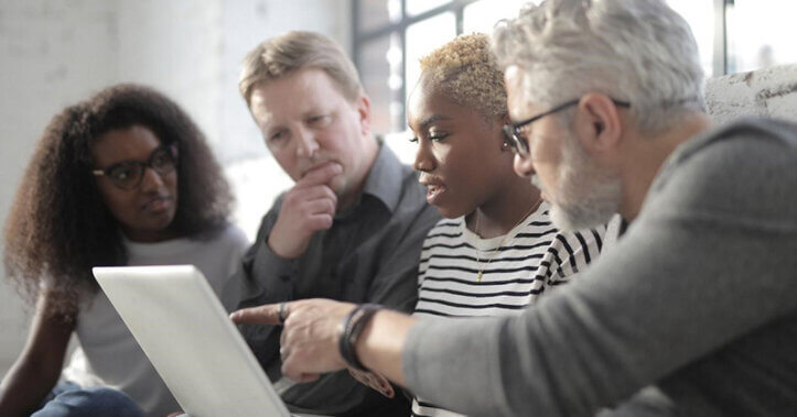 Professionals working together, reviewing something on a laptop.