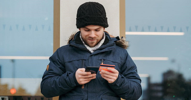 Man holding a credit card makes a purchase on a mobile device.