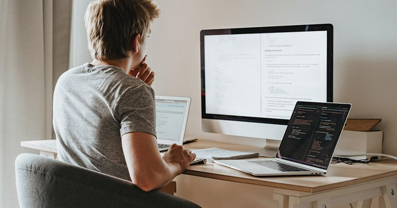 Man sits at desk optimizing a website on a laptop. 