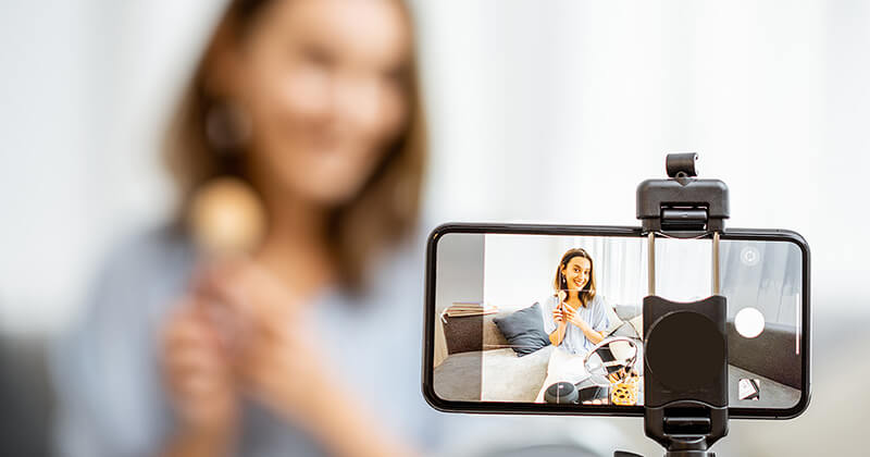 Woman recording a video of her promoting a product.