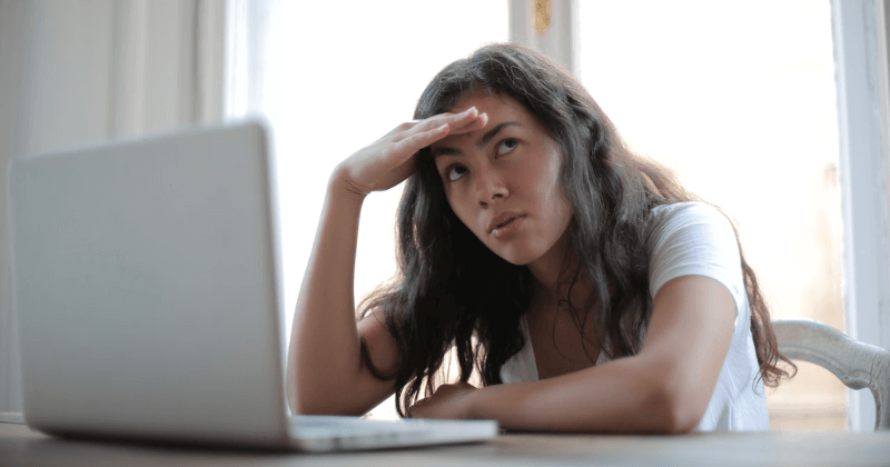 Woman with concerned look working on laptop.