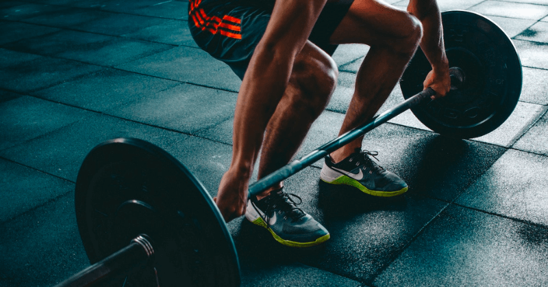 Man squatting to lift a barbell.