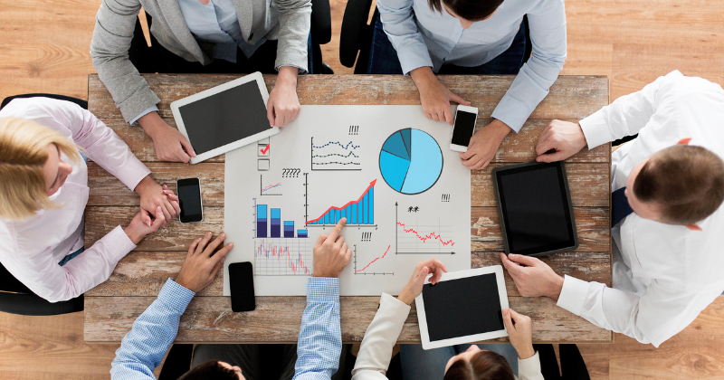 Professionals reviewing data and analytics around a a table.