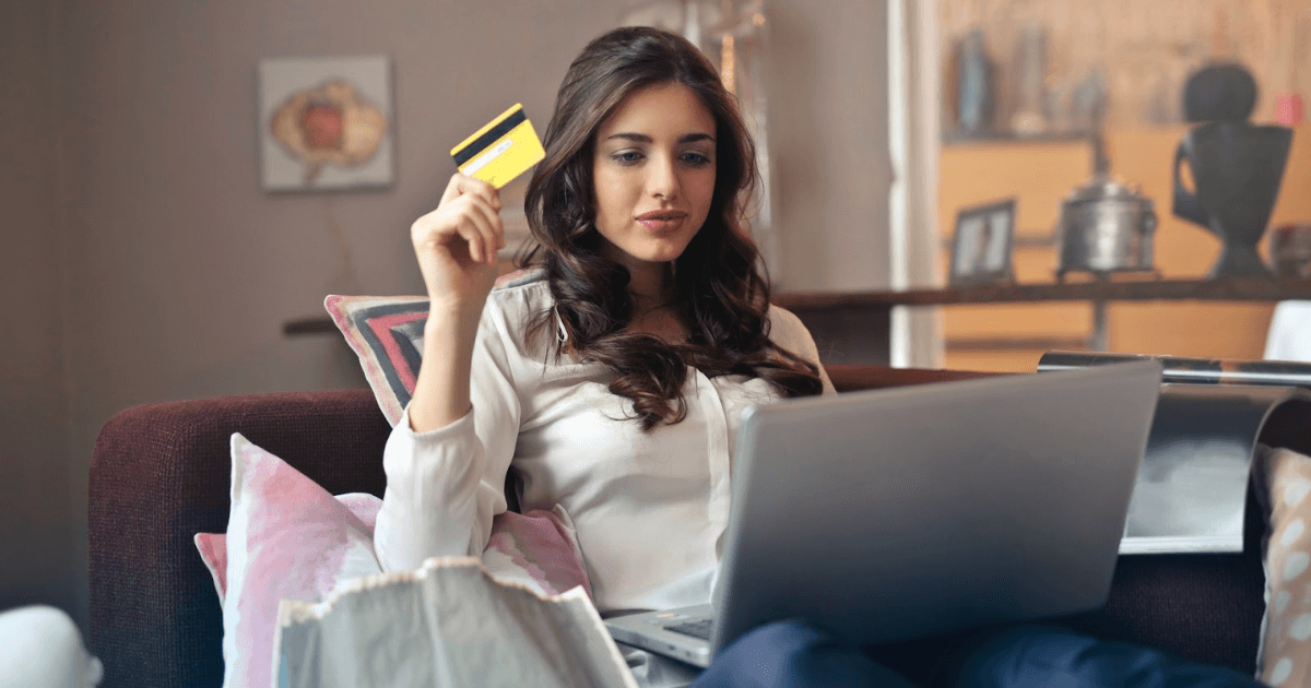 Woman holding credit card shopping on laptop.