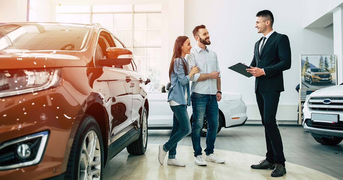 young couple buying new car in car dealership.