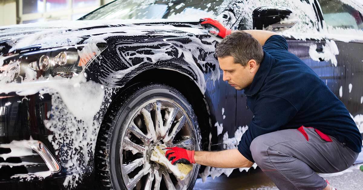 car wash employee washing and detailing car.