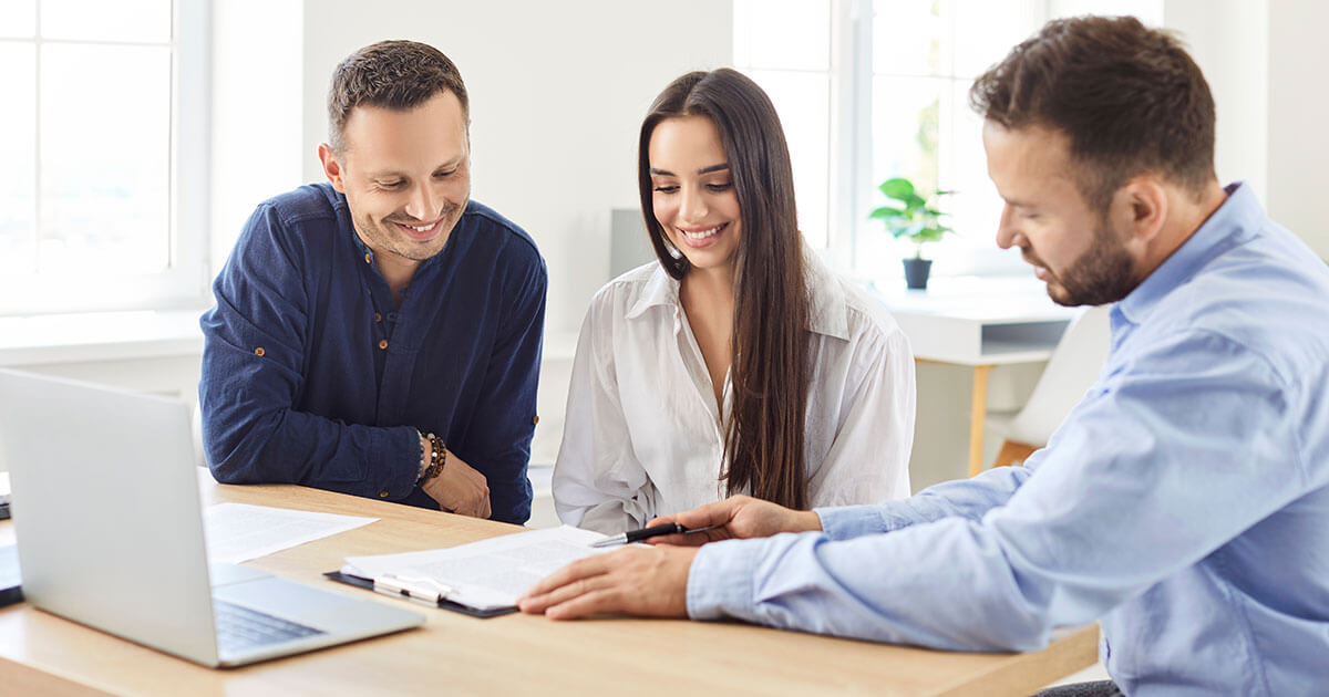 professional meeting with smiling clients reviewing documents.