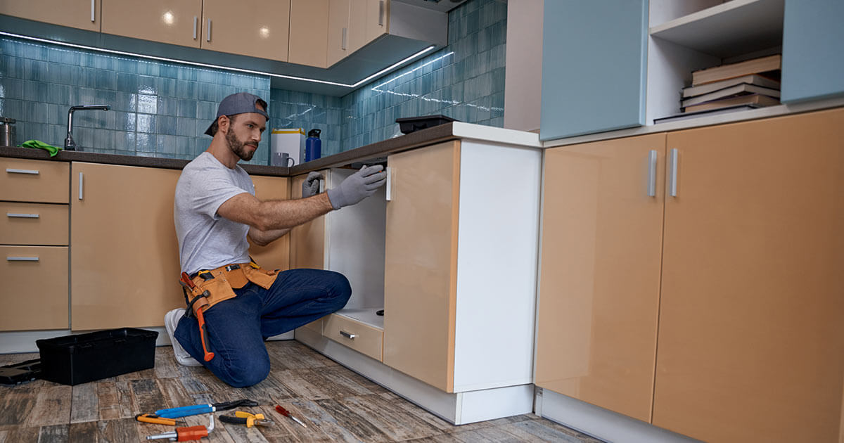 handyman working on kitchen cabinet.