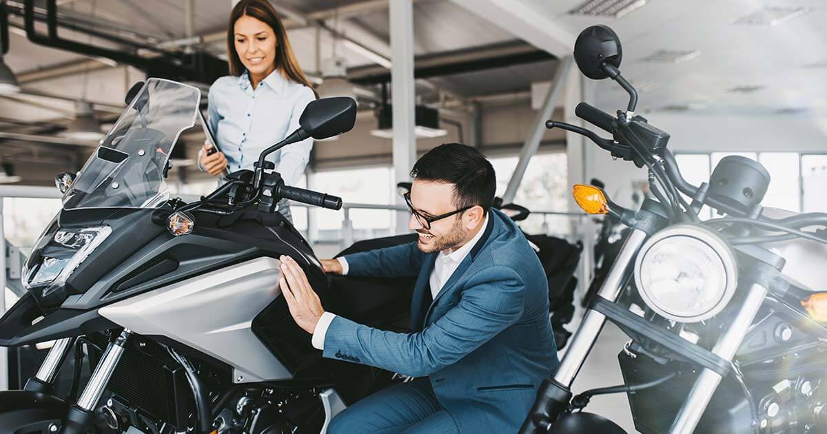 motorcycle dealership saleswoman showing a motorcycle to a customer.
