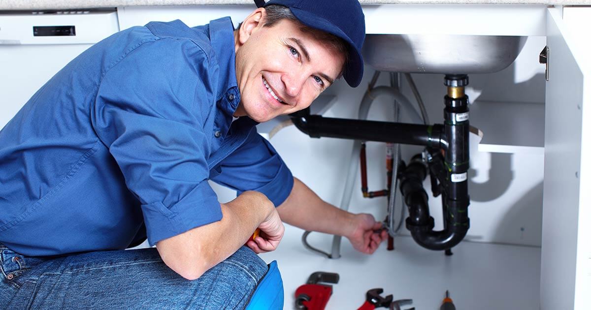 plumber working under a sink.