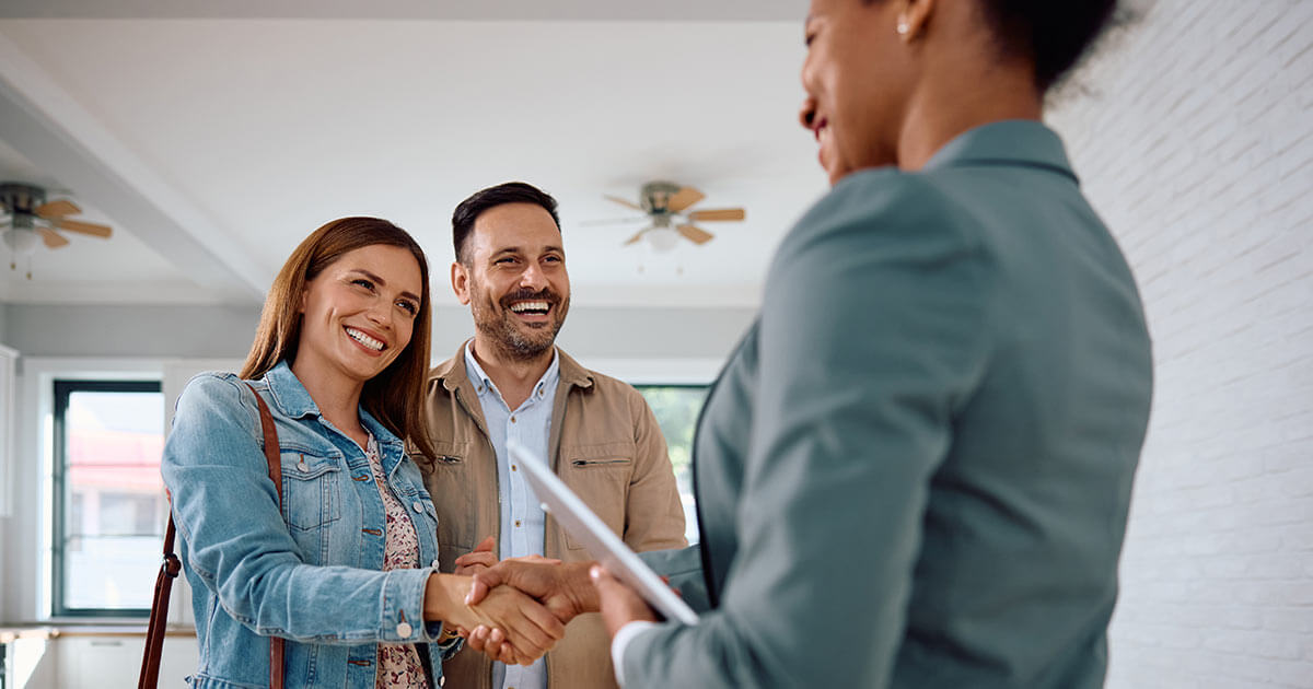 smiling woman with happy husband shaking hands with real estate agent.
