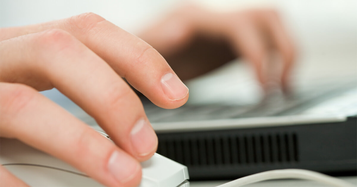 one hand typing on keyboard while the other holds a mouse.