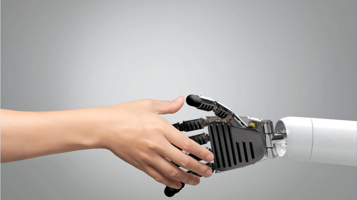 Close-up of a human hand reaching out to shake hands with a robotic prosthetic hand, symbolizing human-AI collaboration.