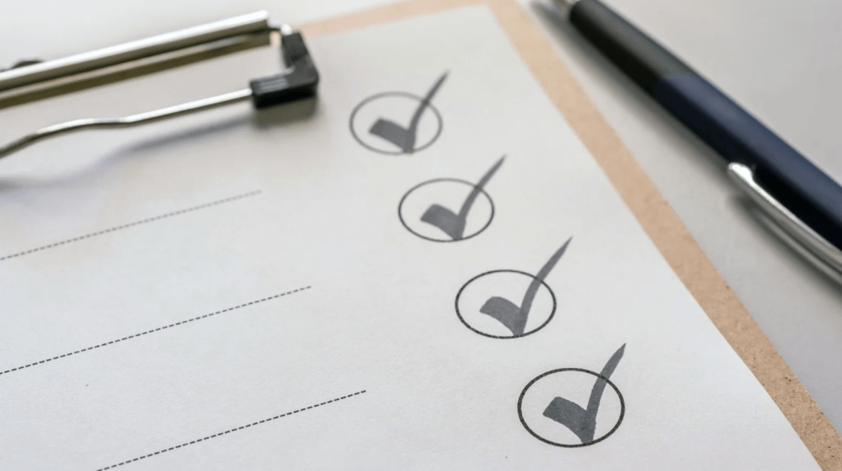 A checklist on a clipboard with three circles marked with checkmarks, placed next to a pen.