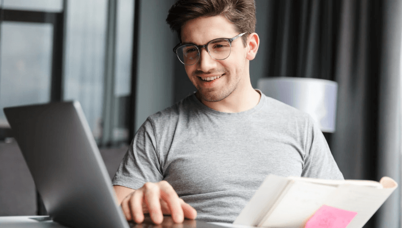 Content creator researching SEO best practices on a laptop while taking notes in a bright home office.