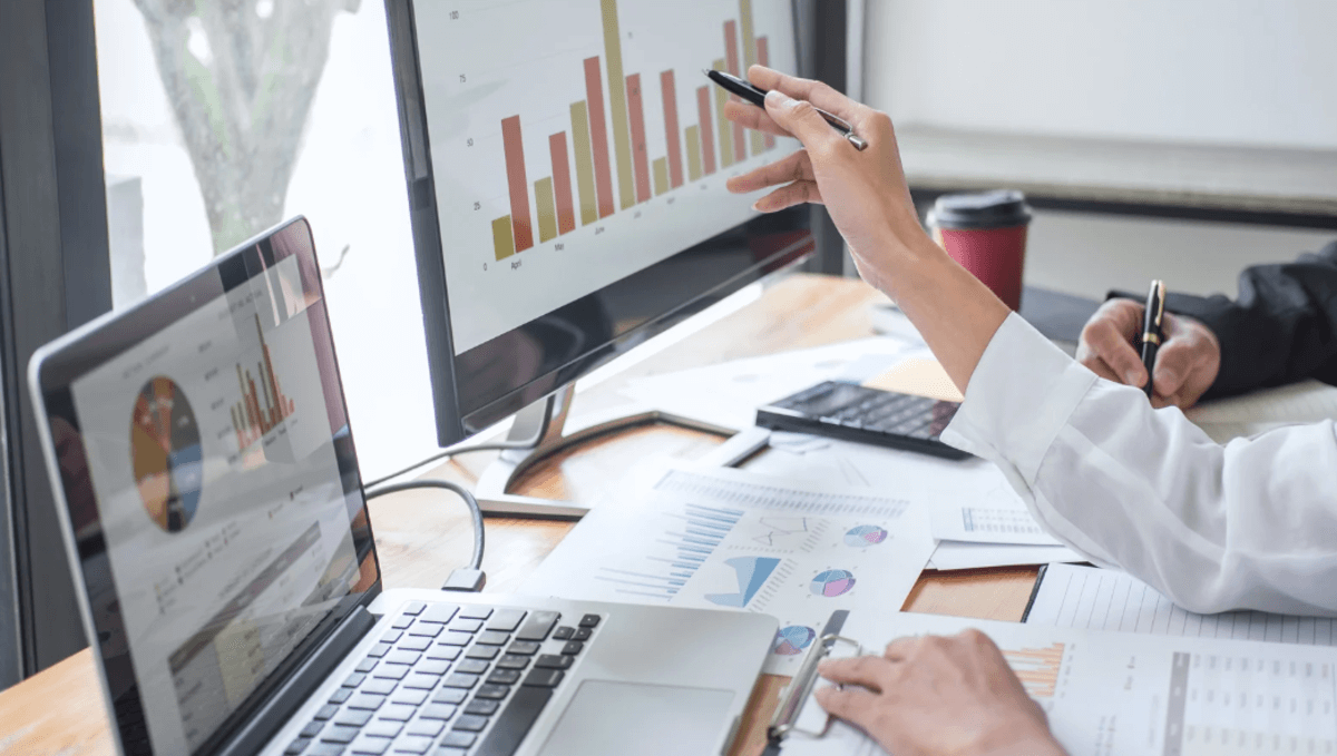 SEO specialist reviewing website analytics dashboards on dual monitors with charts, graphs, and performance reports.
