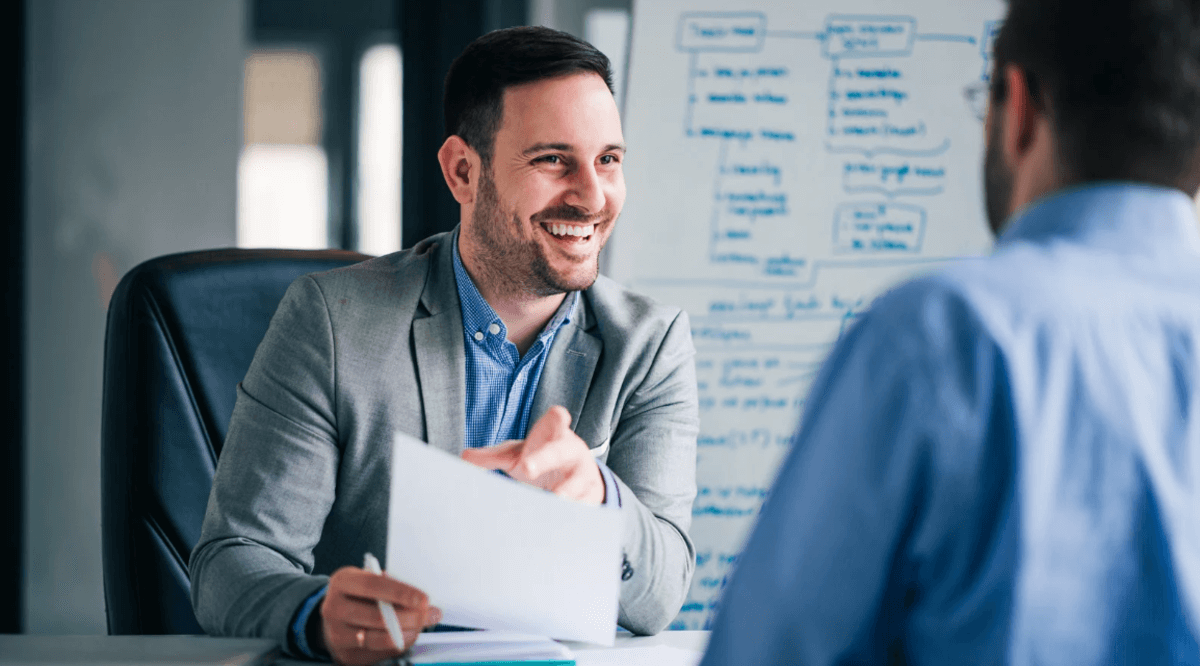 Business professional discussing strategy with a client during an in-person consultation, reviewing documents in a modern office setting.