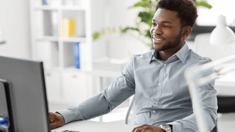 Digital marketing professional working at a desktop computer in a bright office, focused on analytics and performance.