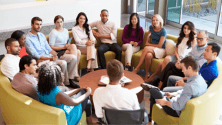 Diverse group of professionals seated in a circle having a team discussion in a modern office meeting space
