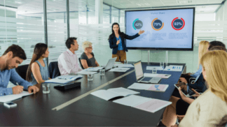 Business presentation showing market share charts on a screen during a strategy meeting with a marketing and analytics team