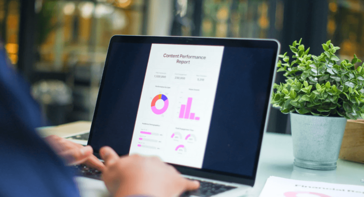 A laptop screen displaying a Content Performance Report with colorful pie charts, bar graphs, and audience demographic data.