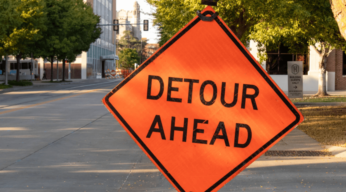 A road sign with the words 'Detour Ahead'