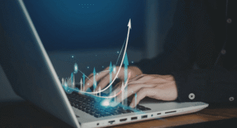Close-up view of hands typing on a laptop keyboard with a glowing, digital 3D overlay of multiple growth arrows pointing upwards, symbolizing data analytics, success, or financial progression.
